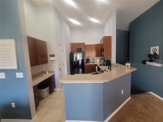 kitchen with kitchen peninsula, a towering ceiling, sink, refrigerator with ice dispenser, and light tile patterned floors