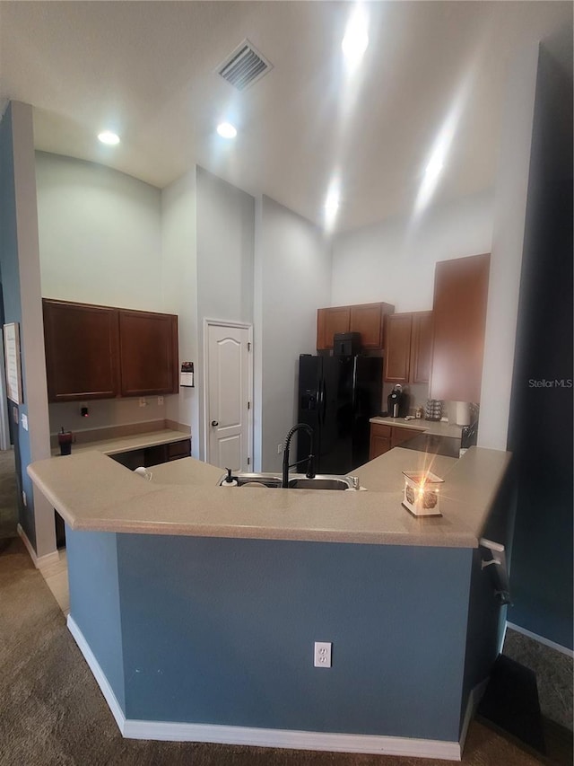 kitchen with kitchen peninsula, black refrigerator with ice dispenser, sink, and carpet floors