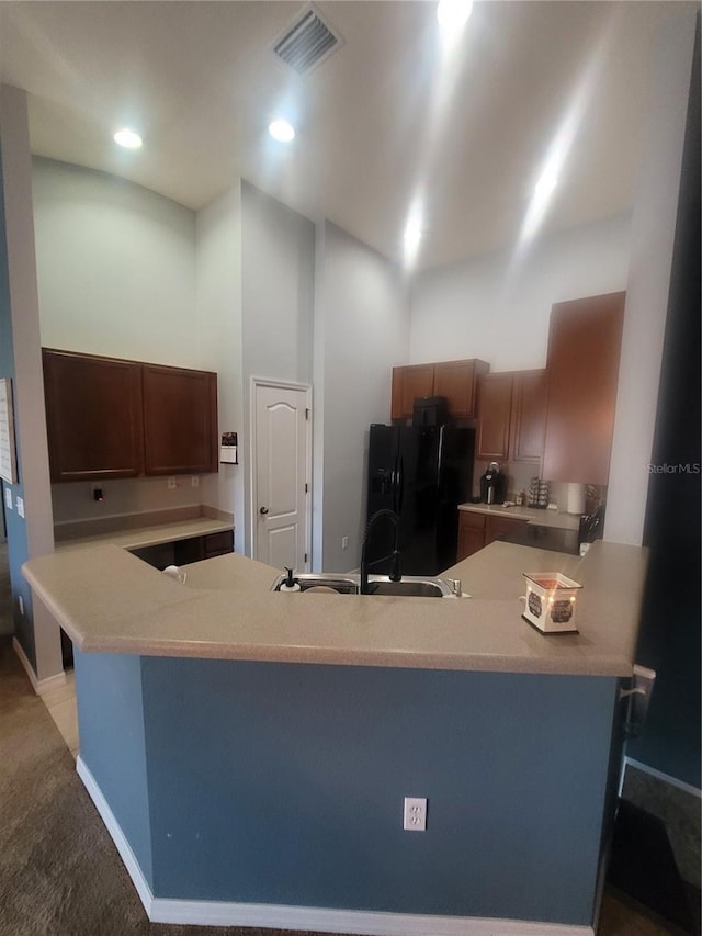 kitchen with kitchen peninsula, black refrigerator with ice dispenser, and sink