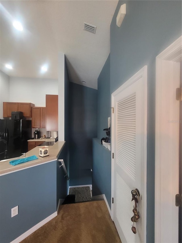 kitchen featuring black refrigerator and dark colored carpet