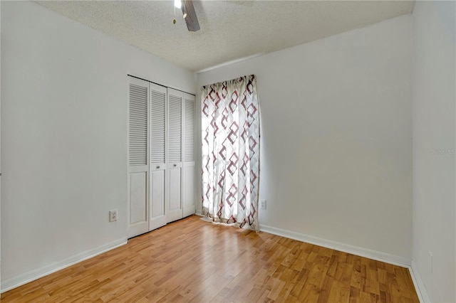 unfurnished bedroom with light wood-type flooring, a textured ceiling, a closet, and ceiling fan