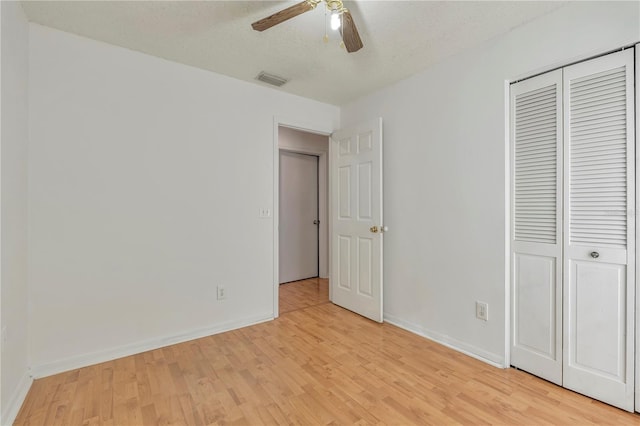 unfurnished bedroom with a closet, ceiling fan, light hardwood / wood-style flooring, and a textured ceiling