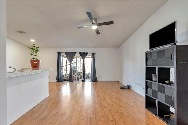 unfurnished living room featuring ceiling fan, wood-type flooring, and a textured ceiling