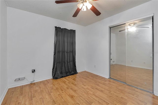 unfurnished bedroom with ceiling fan, a closet, a textured ceiling, and light wood-type flooring