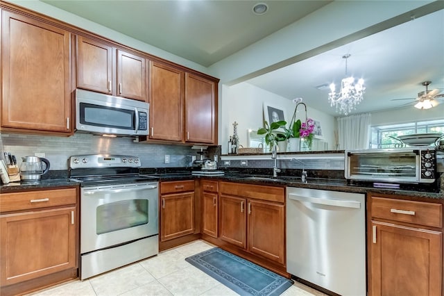 kitchen featuring dark stone counters, sink, decorative backsplash, light tile patterned floors, and stainless steel appliances