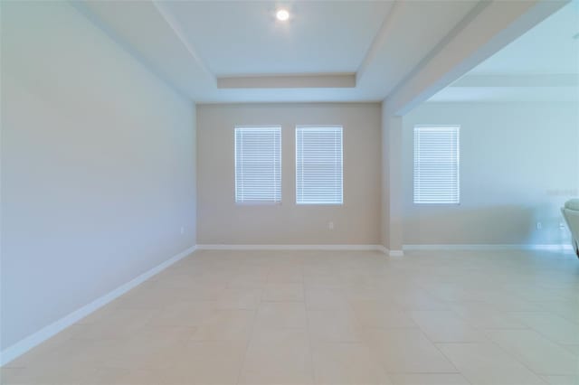 tiled spare room featuring a raised ceiling