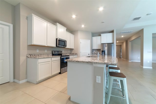 kitchen featuring stainless steel appliances, white cabinetry, a kitchen island with sink, and sink