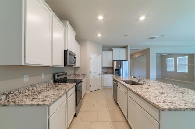 kitchen featuring white cabinets, sink, stainless steel appliances, and an island with sink