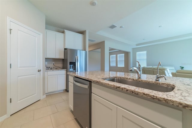 kitchen with light stone countertops, stainless steel appliances, white cabinetry, and sink