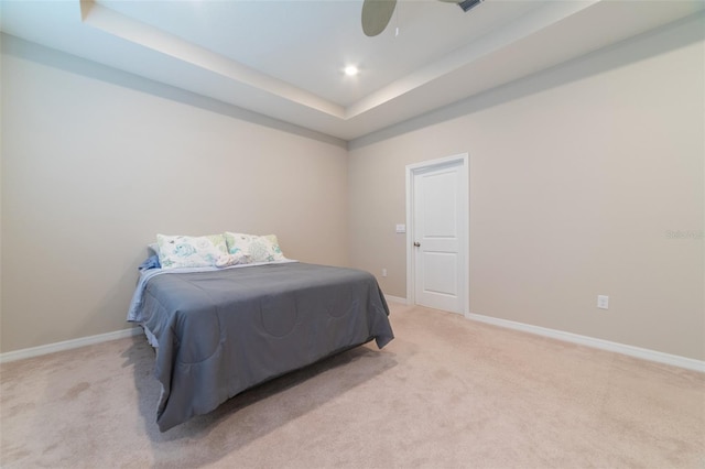 carpeted bedroom featuring a tray ceiling and ceiling fan