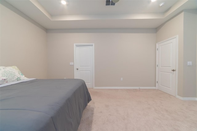 bedroom featuring light carpet and a raised ceiling