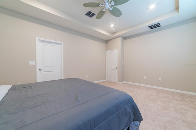 carpeted bedroom featuring a raised ceiling and ceiling fan