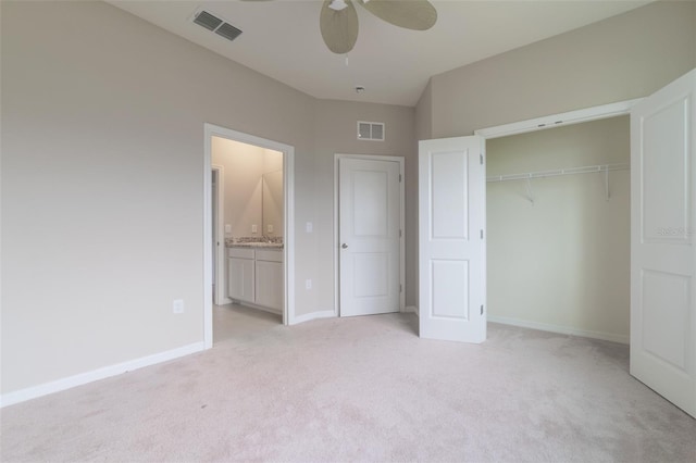 unfurnished bedroom with a closet, ensuite bath, ceiling fan, and light colored carpet