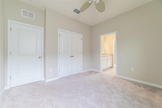 unfurnished bedroom featuring connected bathroom, ceiling fan, a closet, and light carpet