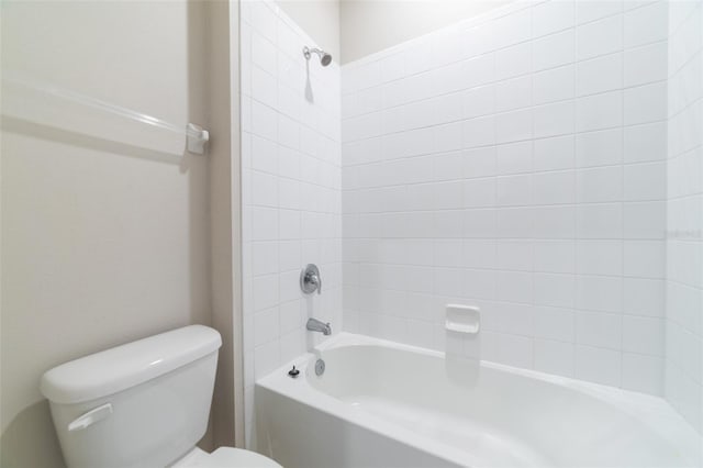 bathroom featuring tiled shower / bath combo and toilet