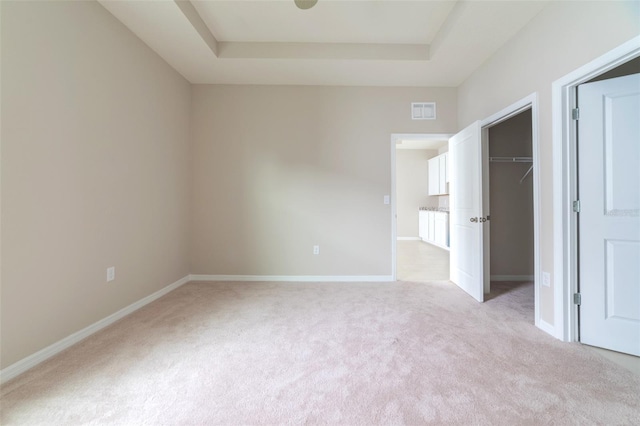 unfurnished room featuring light carpet and a tray ceiling