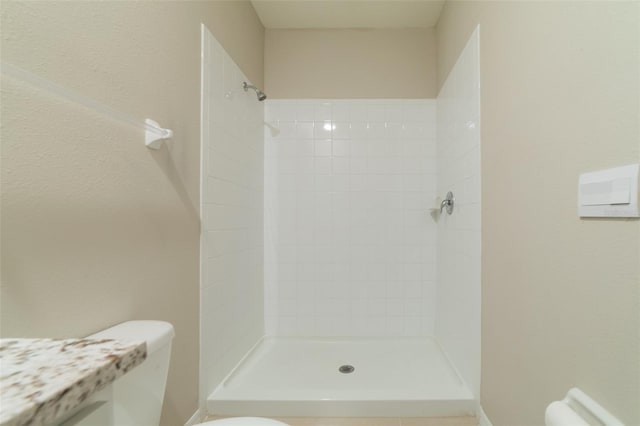 bathroom with tiled shower and toilet