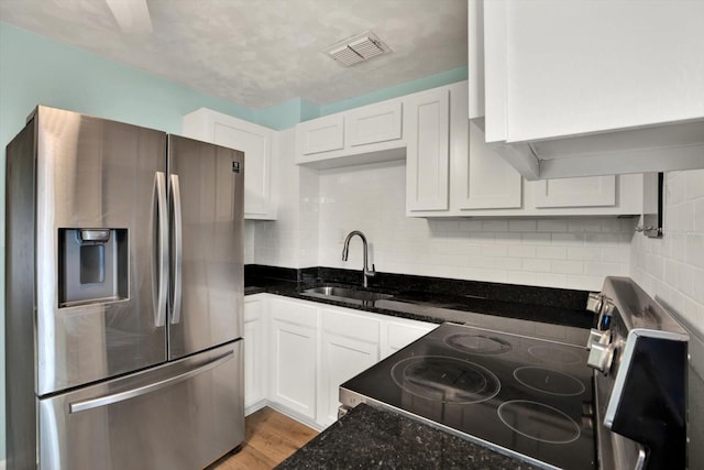 kitchen with white cabinetry, stainless steel fridge, sink, and range with electric stovetop