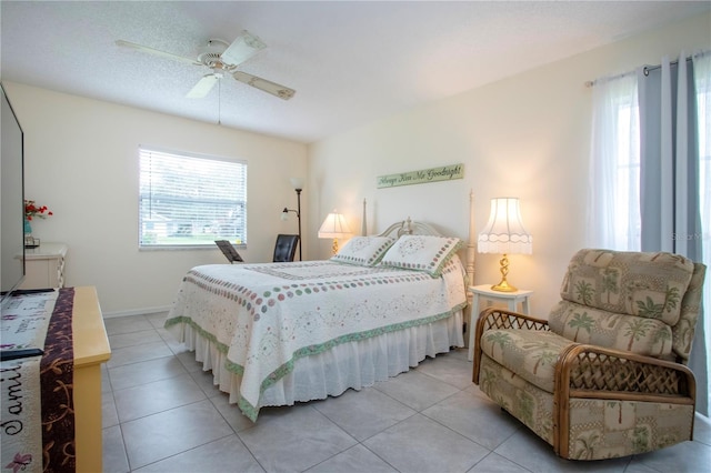 bedroom featuring ceiling fan, light tile patterned flooring, and a textured ceiling