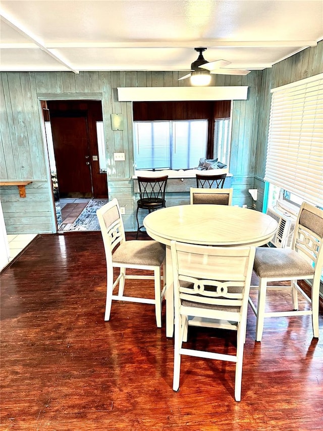 dining space with wood-type flooring, ceiling fan, and wood walls