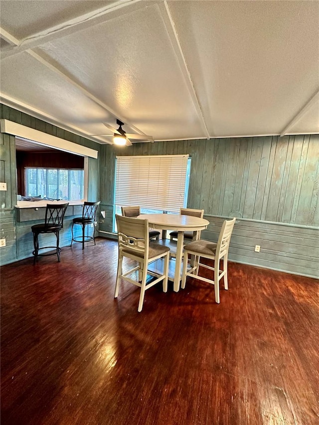 dining area featuring a textured ceiling, dark hardwood / wood-style flooring, ceiling fan, and wood walls