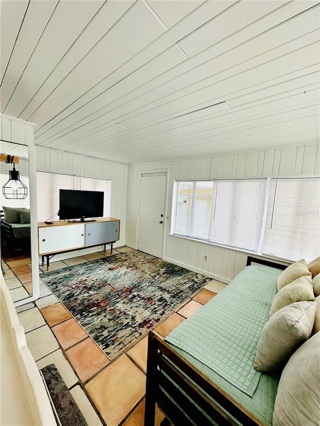 living room featuring wood walls and light tile patterned floors