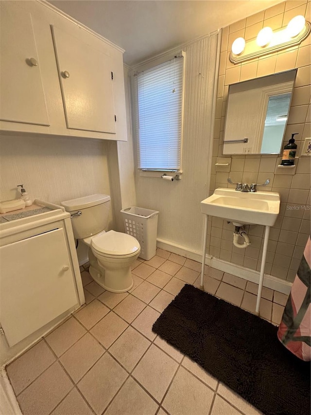 bathroom featuring sink, washer / dryer, tile patterned floors, toilet, and tile walls