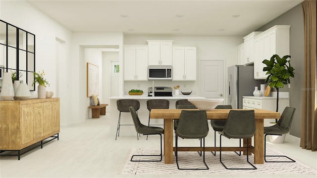 kitchen featuring white cabinets, a breakfast bar, stove, and stainless steel refrigerator