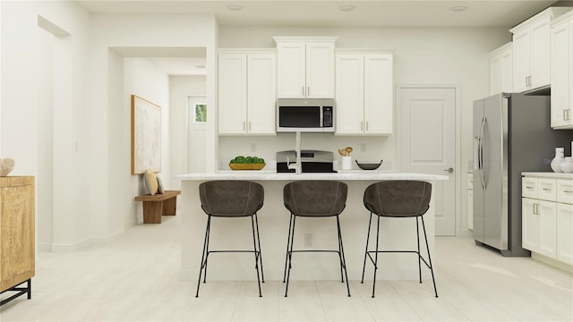 kitchen with a center island with sink, a breakfast bar, white cabinets, and appliances with stainless steel finishes