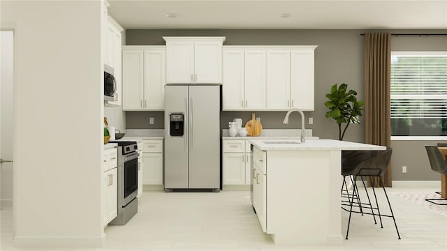 kitchen featuring an island with sink, sink, white cabinets, and stainless steel appliances