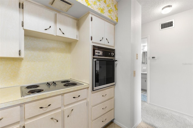 kitchen with black oven, light colored carpet, a textured ceiling, and white electric stovetop