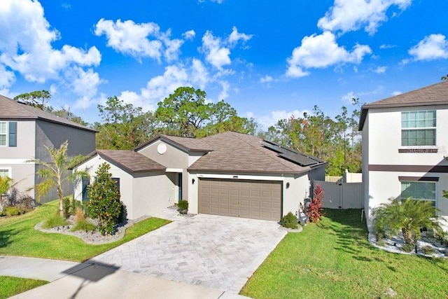 view of front of home with a front yard, solar panels, and a garage