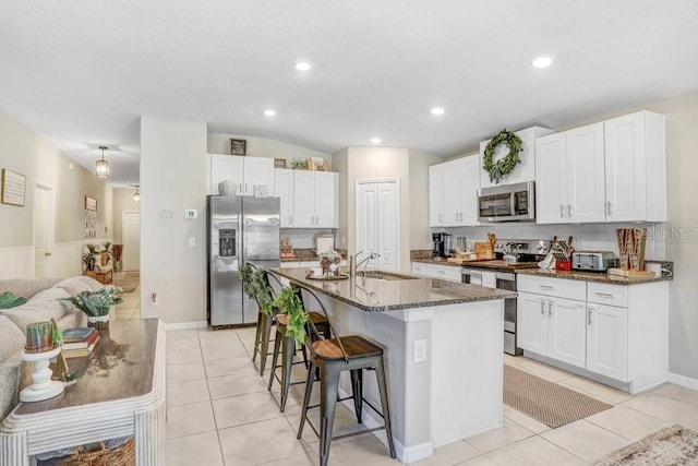 kitchen with stainless steel appliances, white cabinetry, and light tile patterned flooring