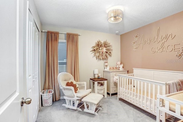 bedroom with a crib, carpet, a textured ceiling, and a closet