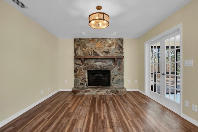 unfurnished living room with a stone fireplace, french doors, and hardwood / wood-style floors