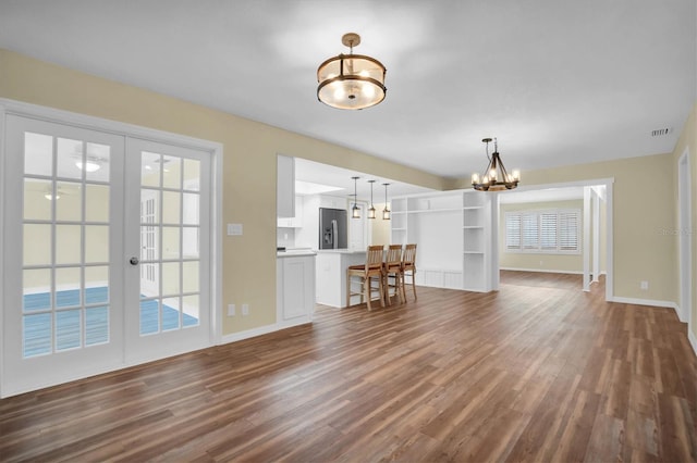 unfurnished living room with french doors, dark hardwood / wood-style floors, and a notable chandelier