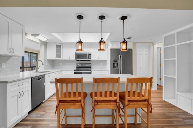 kitchen with white cabinets, appliances with stainless steel finishes, a kitchen island, and sink