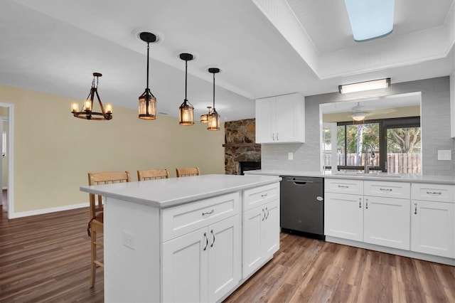 kitchen with a breakfast bar, white cabinets, hanging light fixtures, and dishwasher