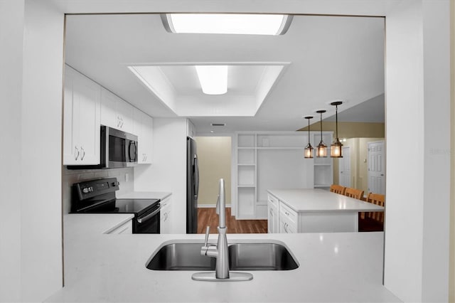 kitchen featuring white cabinets, stainless steel appliances, kitchen peninsula, and sink