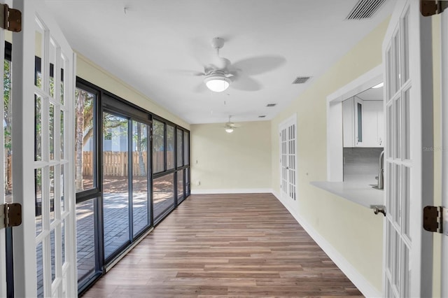 unfurnished sunroom with ceiling fan and french doors