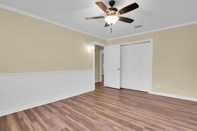 unfurnished bedroom with ceiling fan, light hardwood / wood-style floors, crown molding, and a closet