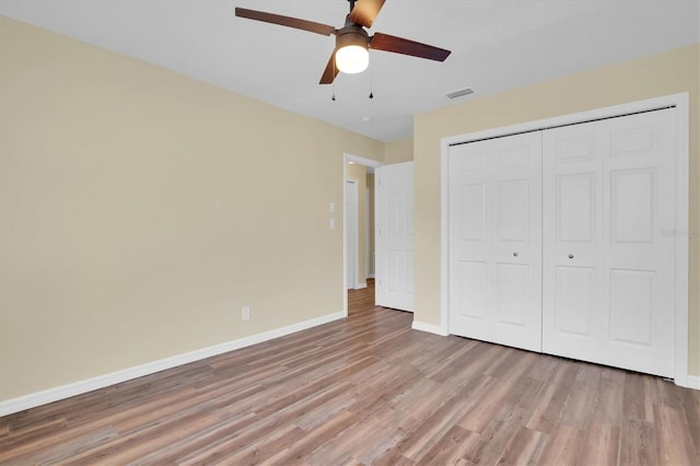 unfurnished bedroom featuring ceiling fan, a closet, and light wood-type flooring