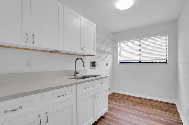 washroom with sink, cabinets, washer hookup, hookup for an electric dryer, and light wood-type flooring