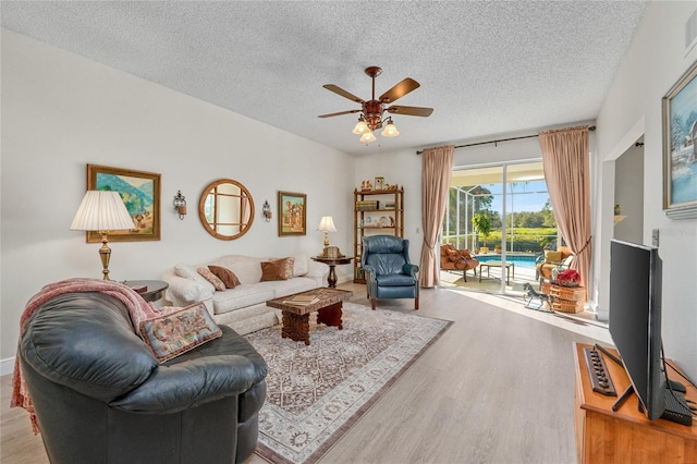 living room with a textured ceiling, light hardwood / wood-style flooring, and ceiling fan