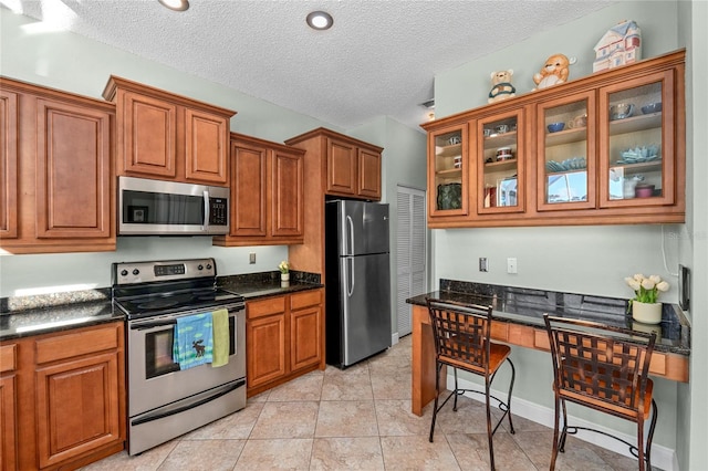 kitchen with a textured ceiling, light tile patterned flooring, and stainless steel appliances