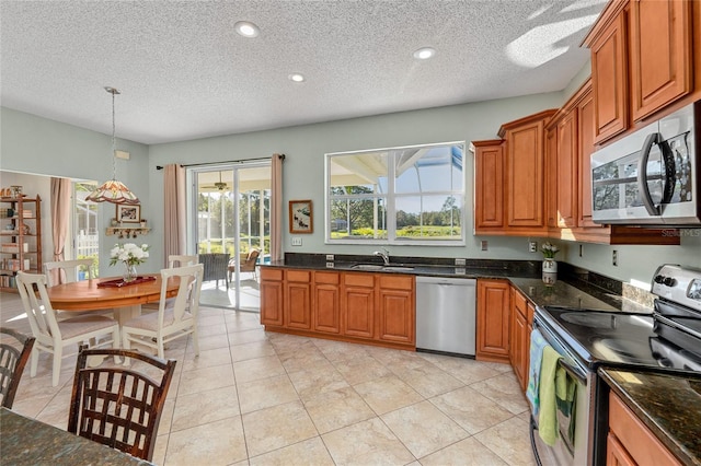 kitchen with a textured ceiling, sink, hanging light fixtures, and appliances with stainless steel finishes