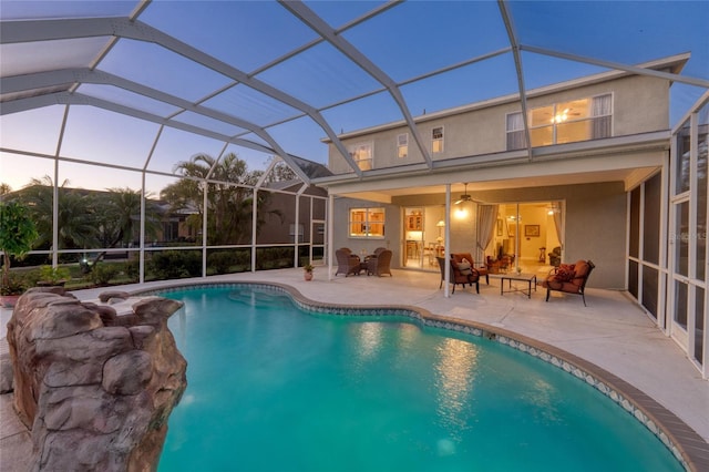 pool at dusk featuring outdoor lounge area, ceiling fan, a patio area, and a lanai