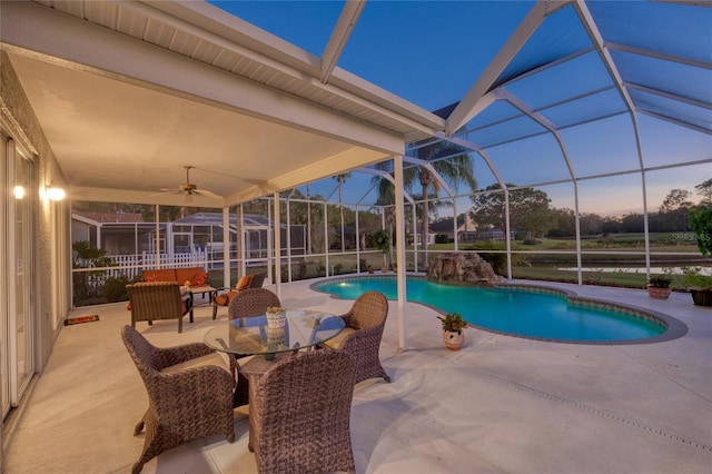 pool at dusk featuring outdoor lounge area, ceiling fan, a lanai, and a patio