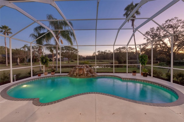 pool at dusk featuring a lanai and a patio