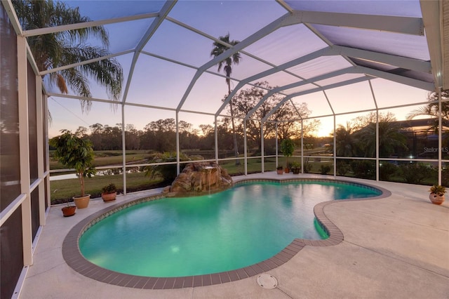 pool at dusk featuring a patio and a lanai